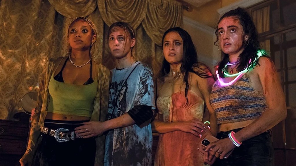 An image from the film Bodies Bodies Bodies. It features a group of four young people. They are dressed in party attire and are covered in bruises, sweat and dirt. They look distressed. 