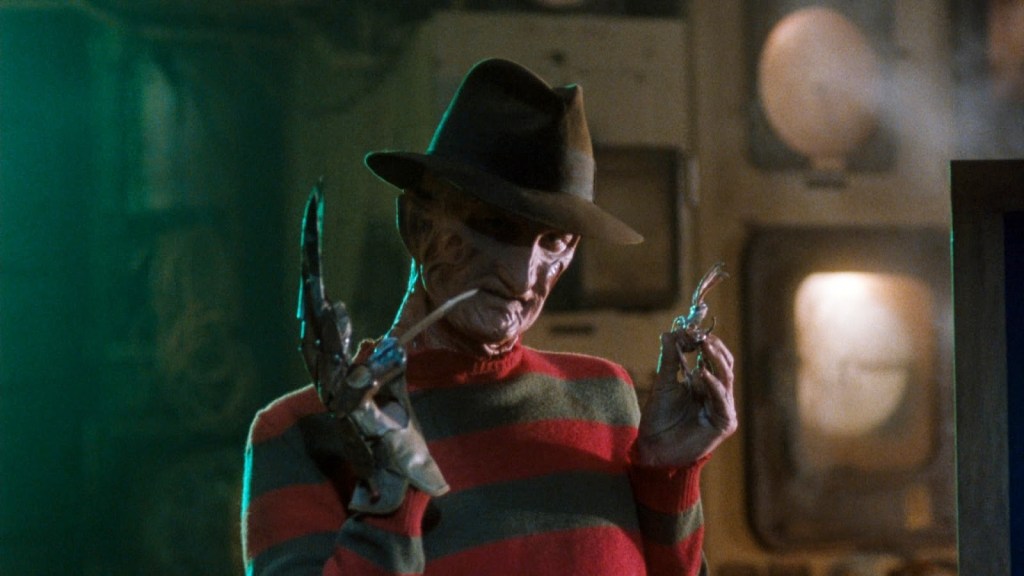 An image from the film Freddy's Dead: The Final Nightmare. It features Freddy Krueger (Robert Englund) standing with hand raised and the blades on his glove spread. 