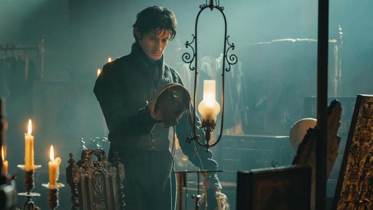 An image from the film The Count of Monte Cristo. It features a man (Pierre Niney) holding and looking at a mask.