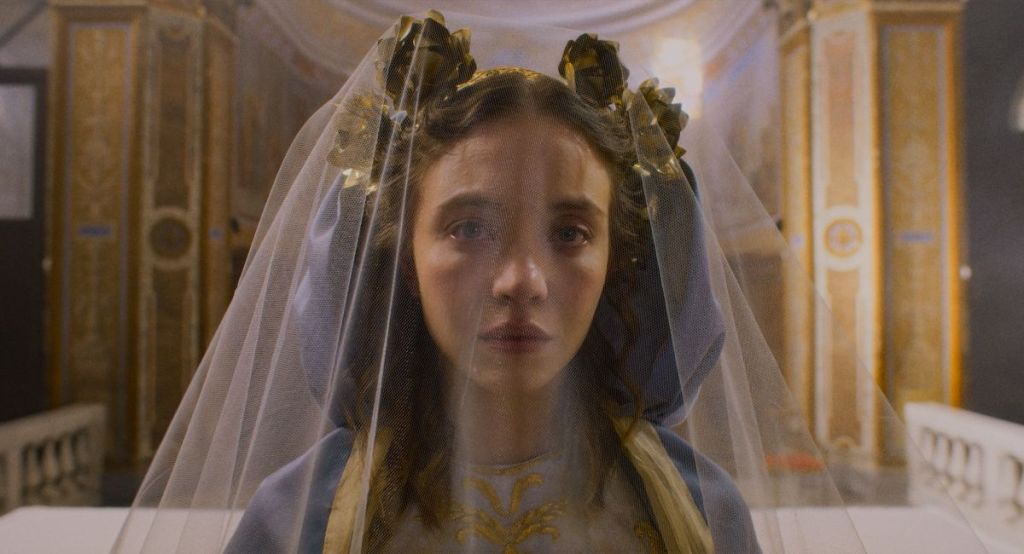 An image from the film Immaculate. It features a woman (Sydney Sweeney) dressed in lavish religious clothing.