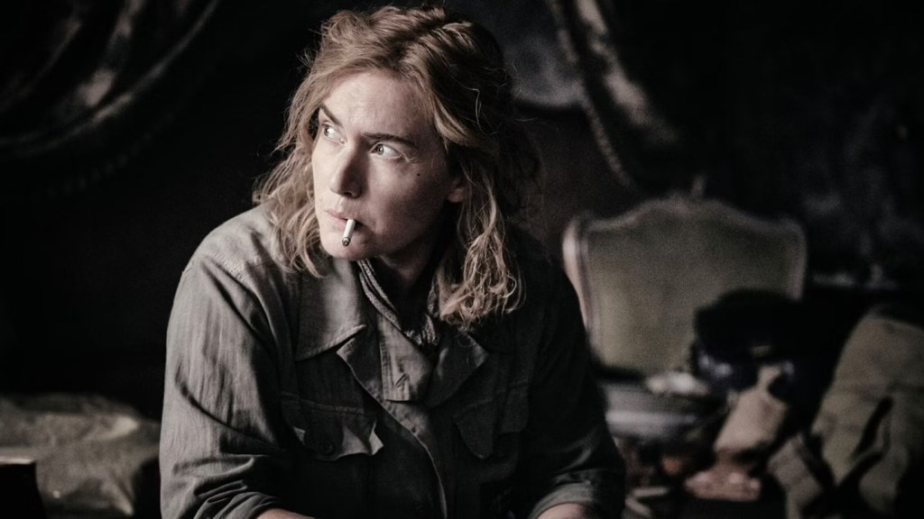 An image from the film Lee. It features a woman (Kate Winslet) smoking in a room that has been bombed.