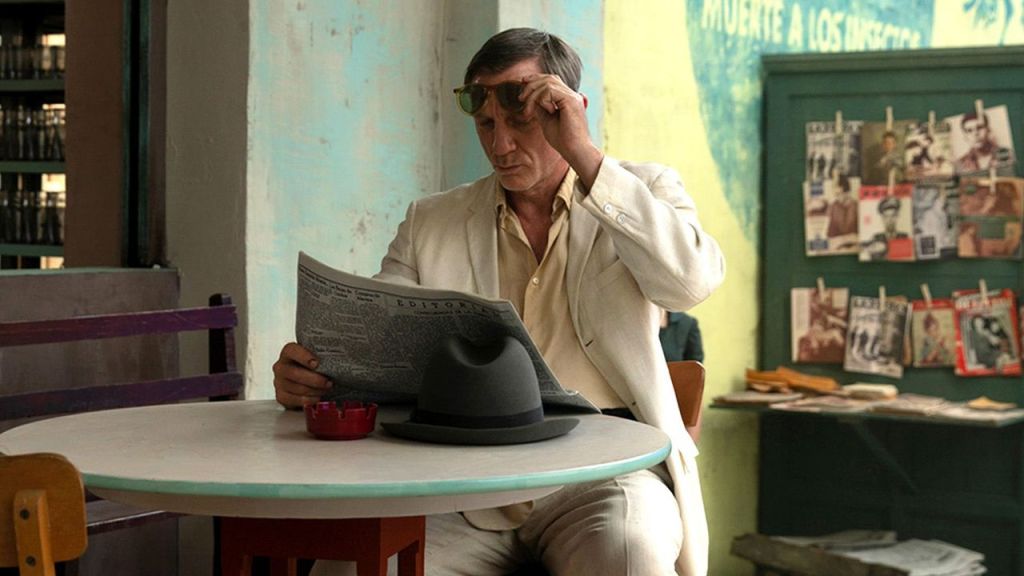 An image from the film Queer. It features a man (Daniel Craig) sitting at a table reading a newspaper.