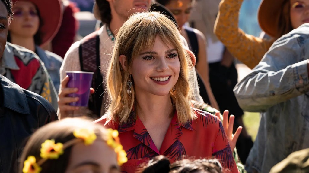 An image from the film The Greatest Hits. It features a woman (Lucy Boynton) standing in a crowd at a music festival.