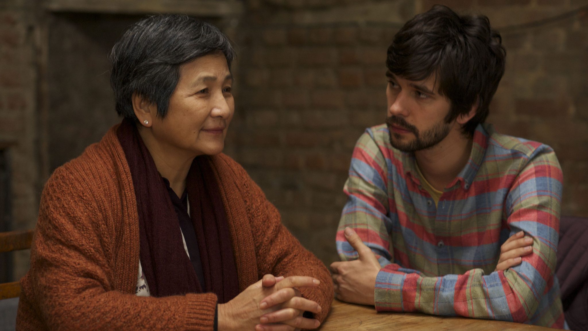An image from the film Lilting. It features a man (Ben Whishaw) and an older woman (Cheng Pei-pei) sitting at a table. 