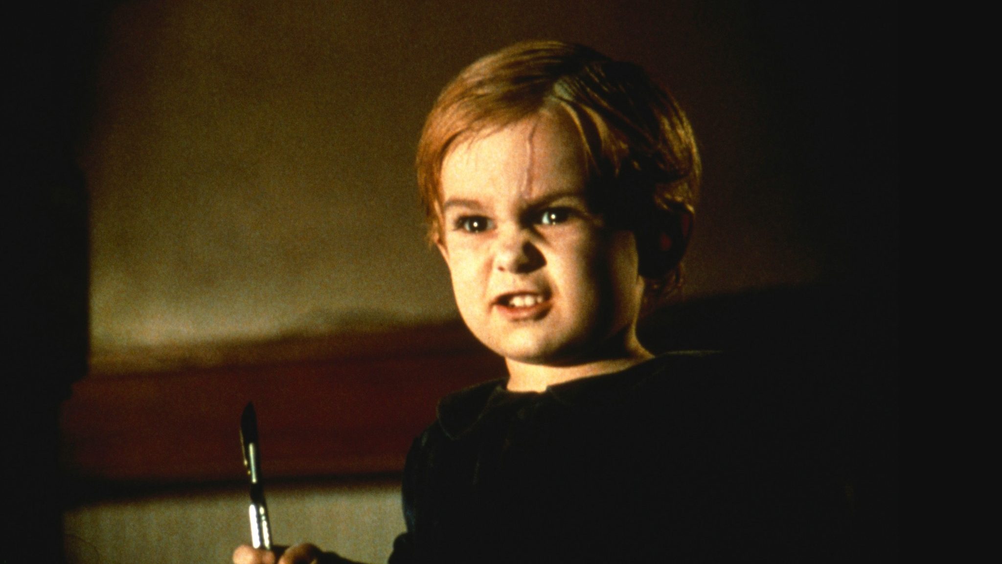 An image from the film Pet Semetary. It features a young child (Miko Hughes) holding a scalpel.