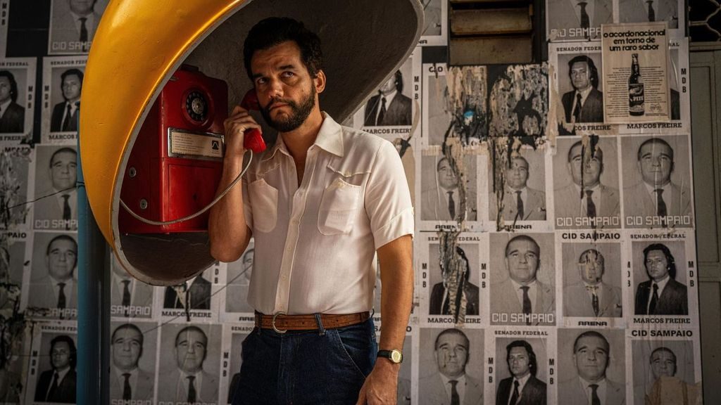 An image from the film The Secret Agent. It features a man (Wagner Moura) on a payphone. 