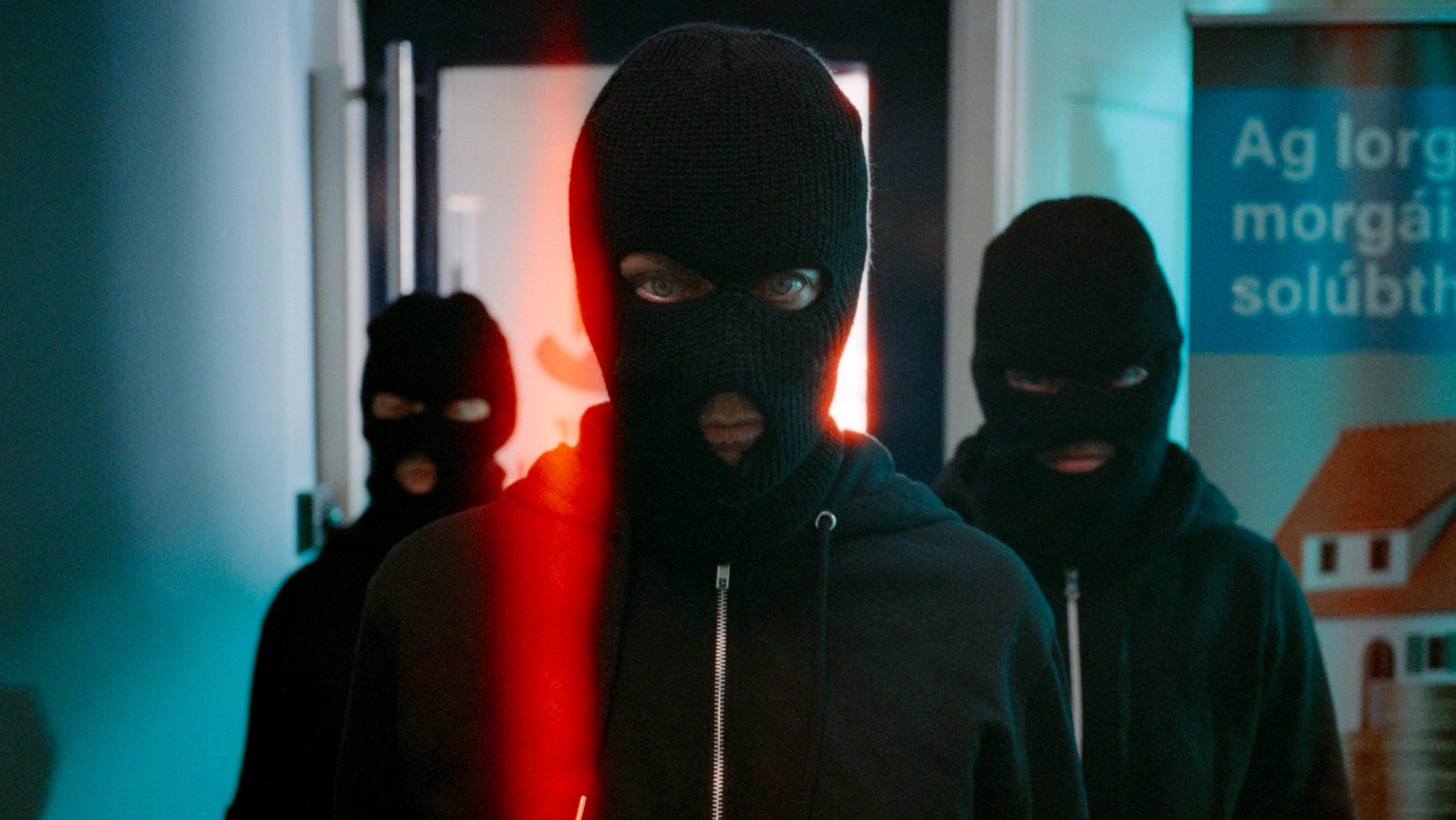 An image from the film Aontas. It features three figures waving balaclavas. 
